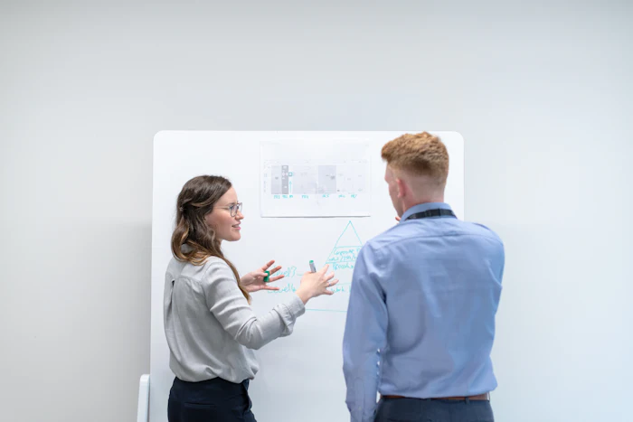 Two colleagues working through ideas at a whiteboard